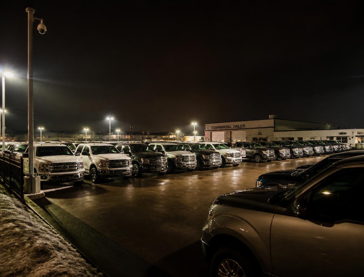 Vehicle lot at night monitored by a pole-mounted surveillance camera